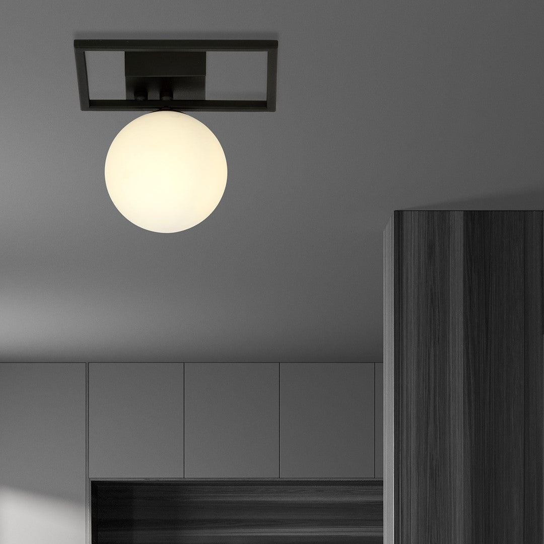 Plafonnier noir et globe opale allumé, installé au plafond au-dessus d'un meuble sombre.
