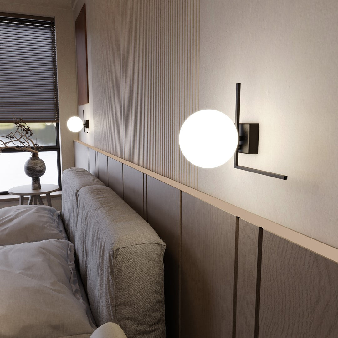 Vue rapprochée d'une applique allumée devant un mur lambrissé cannelé et un lit