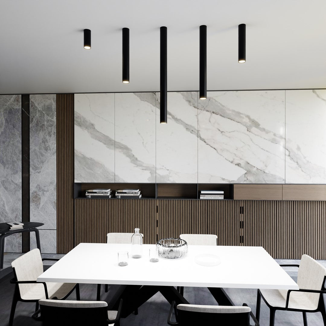 Cinq spots cylindriques noirs de longueurs différentes au-dessus d'une table blanche