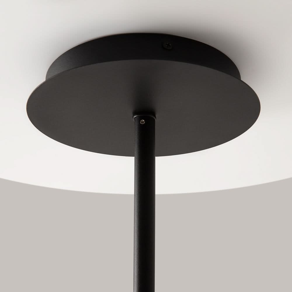 Gros plan de la rosace ronde noire fixée au plafond blanc.