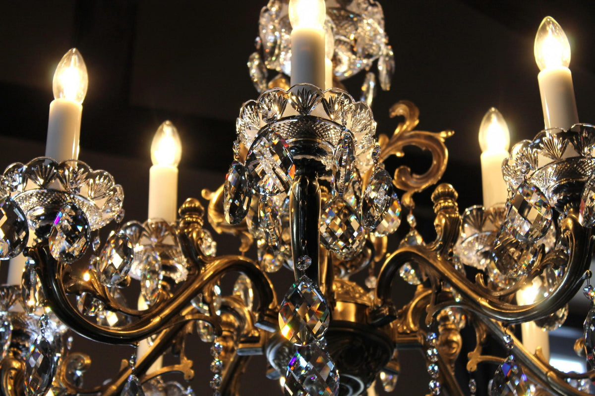 Gros plan du luminaire allumé, ampoules flamme et reflets dorés sur le cristal