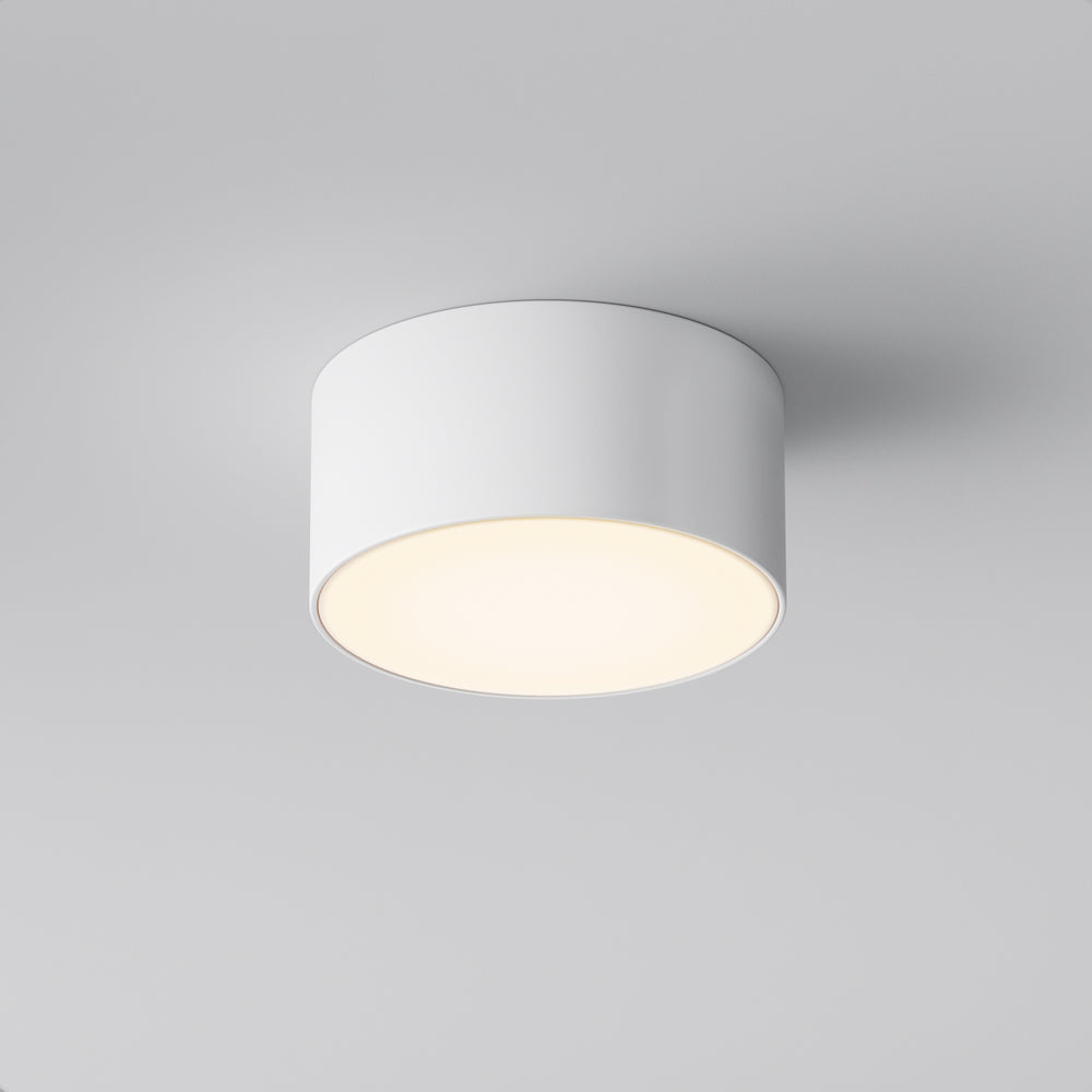 Luminaire blanc vu en plongée sous le plafond, forme cylindrique épurée