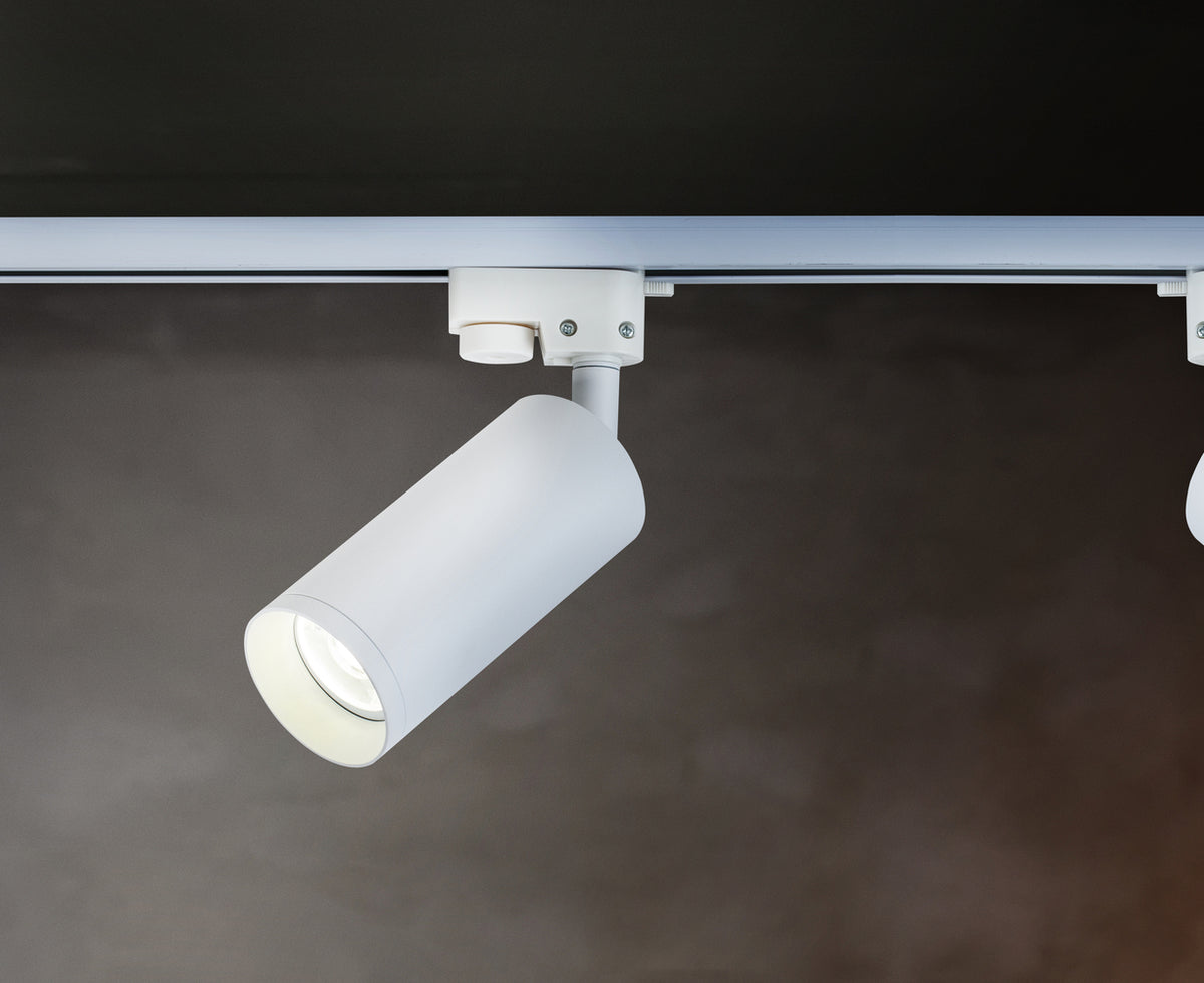 Spot blanc sur rail dans un intérieur sombre, un autre spot à droite.