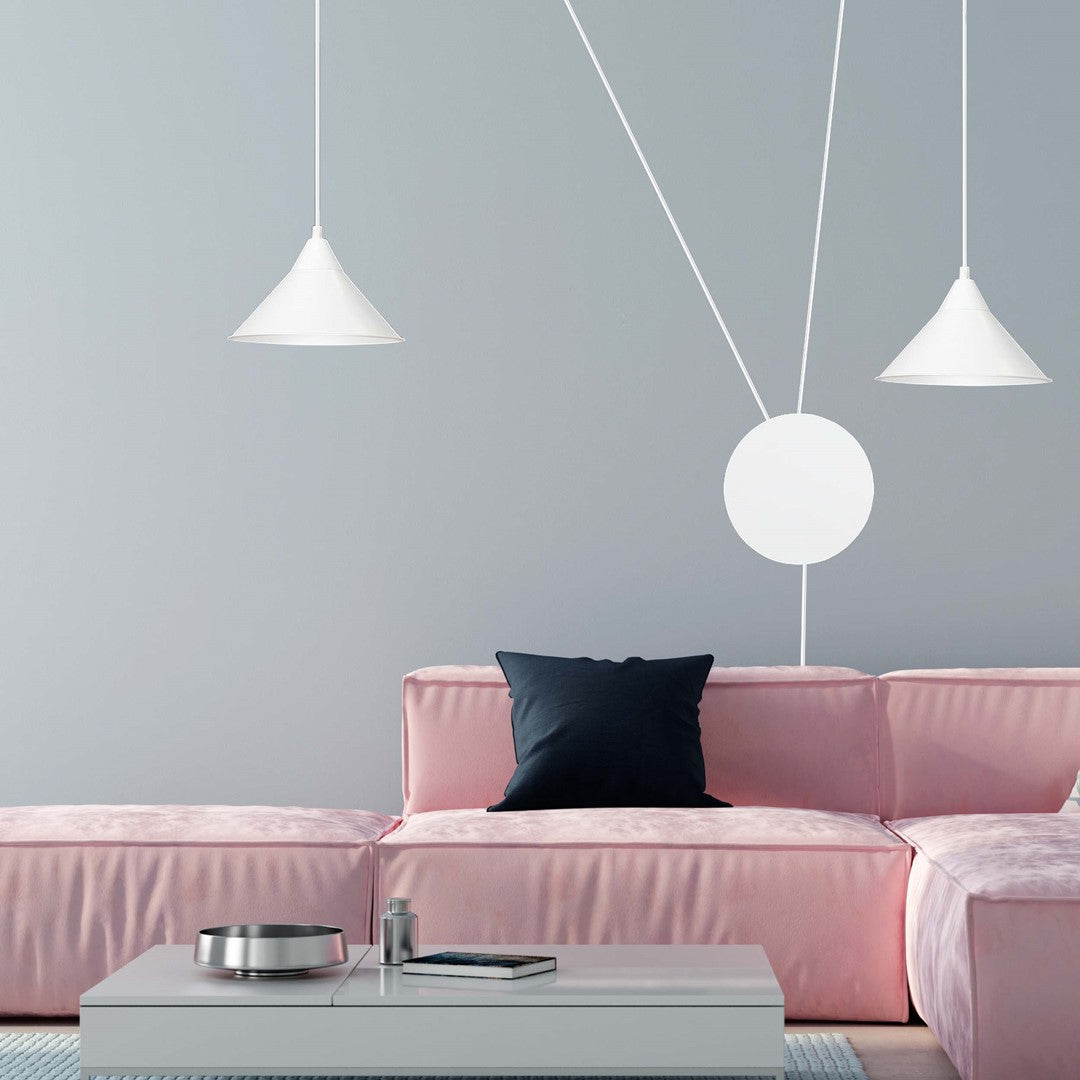 Mise en ambiance salon : canapé rose et coussin foncé sous les deux suspensions blanches.