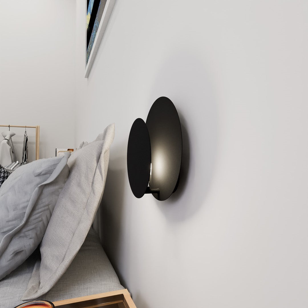 Applique murale noire allumée fixée sur un mur blanc près d'un lit