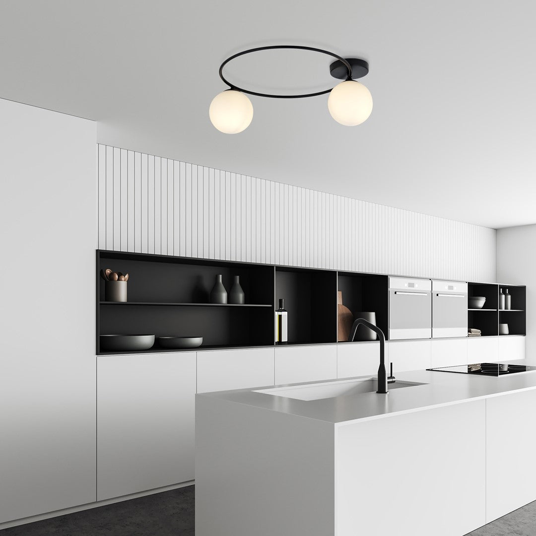 Luminaire allumé fixé au plafond d'une cuisine blanche minimaliste avec îlot central.