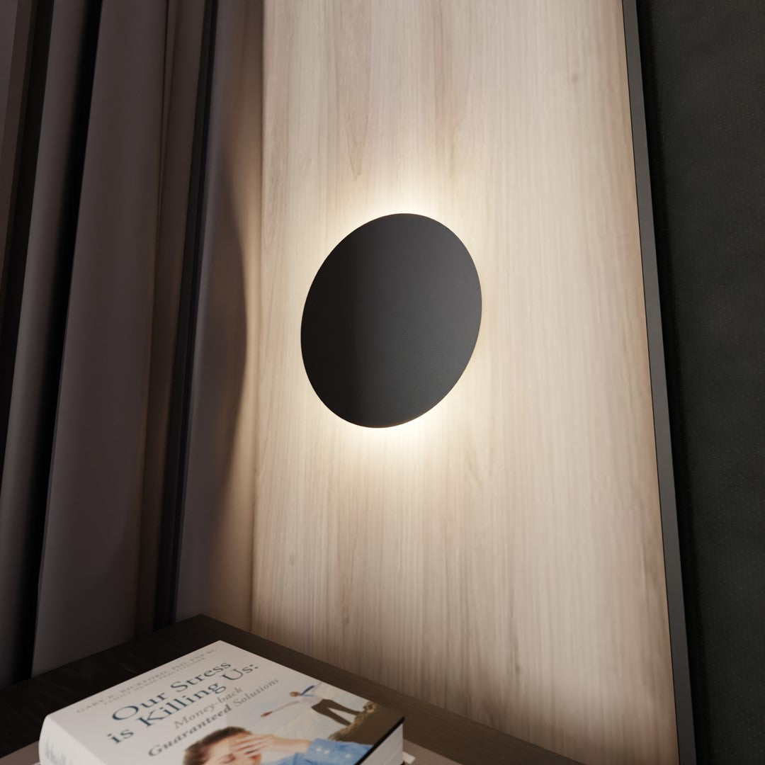 Gros plan de l'applique ronde, lumière rasante contre le mur stratifié clair.