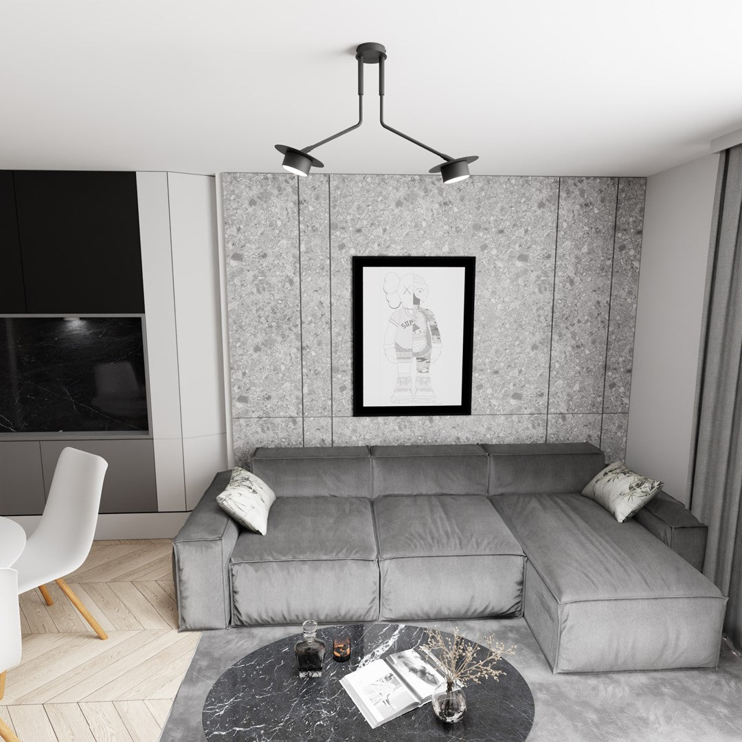 Suspension noire installée au plafond d'un salon gris, au-dessus d'un canapé d'angle.