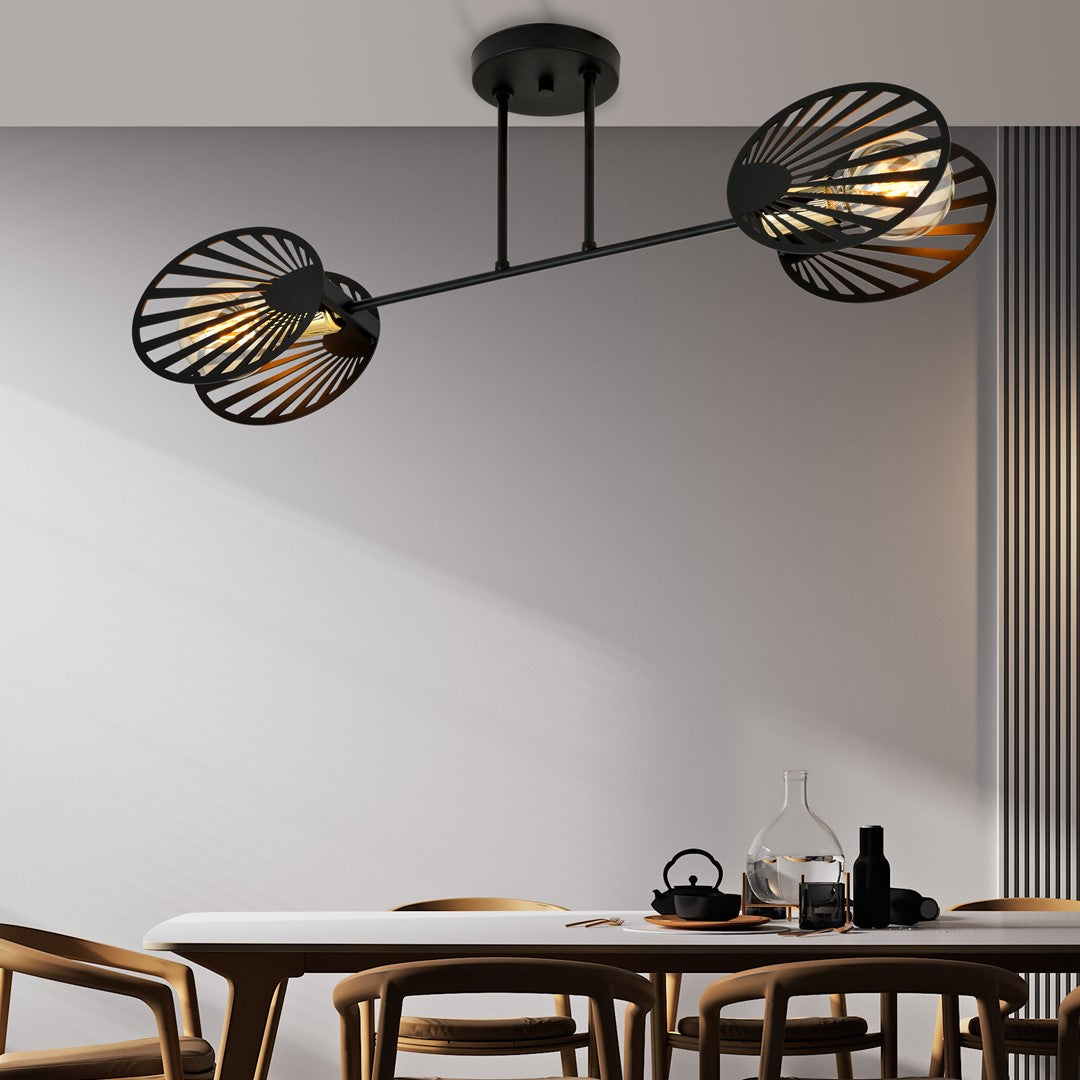 Plafonnier noir allumé au-dessus d'une table dressée avec théière et carafe en verre.