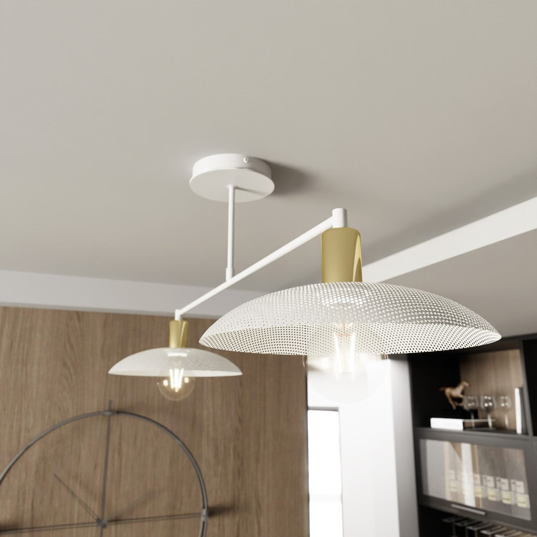 Vue rapprochée des deux diffuseurs blancs et dorés, sous un plafond blanc, avec ampoules visibles.