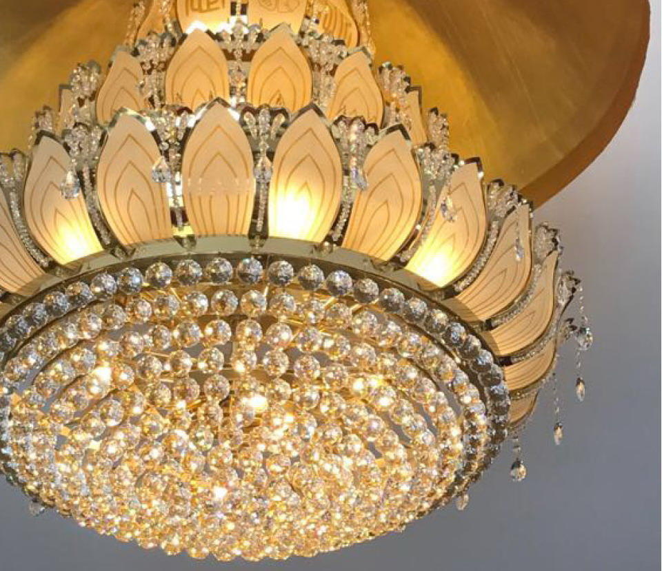 Détail rapproché des pétales lumineux, perles de cristal et finitions dorées du luminaire.