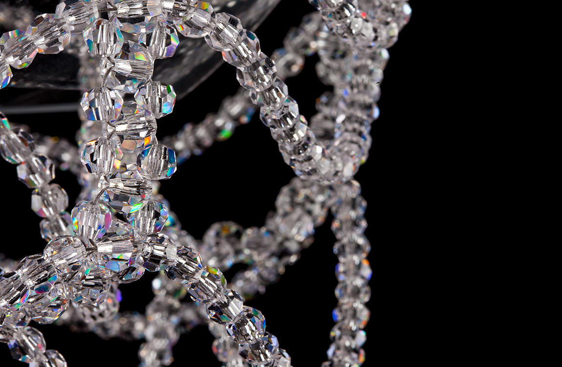 Gros plan sur les perles de cristal taillées aux reflets irisés formant la résille