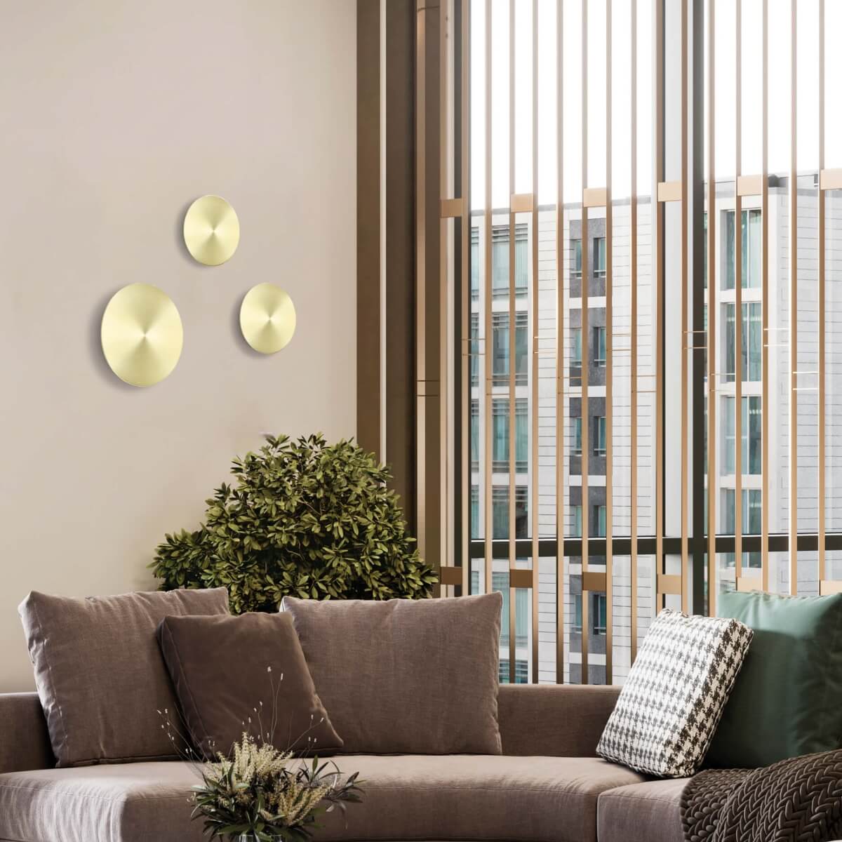 Vue d'ambiance avec trois disques laiton sur mur beige, canapé et baie vitrée