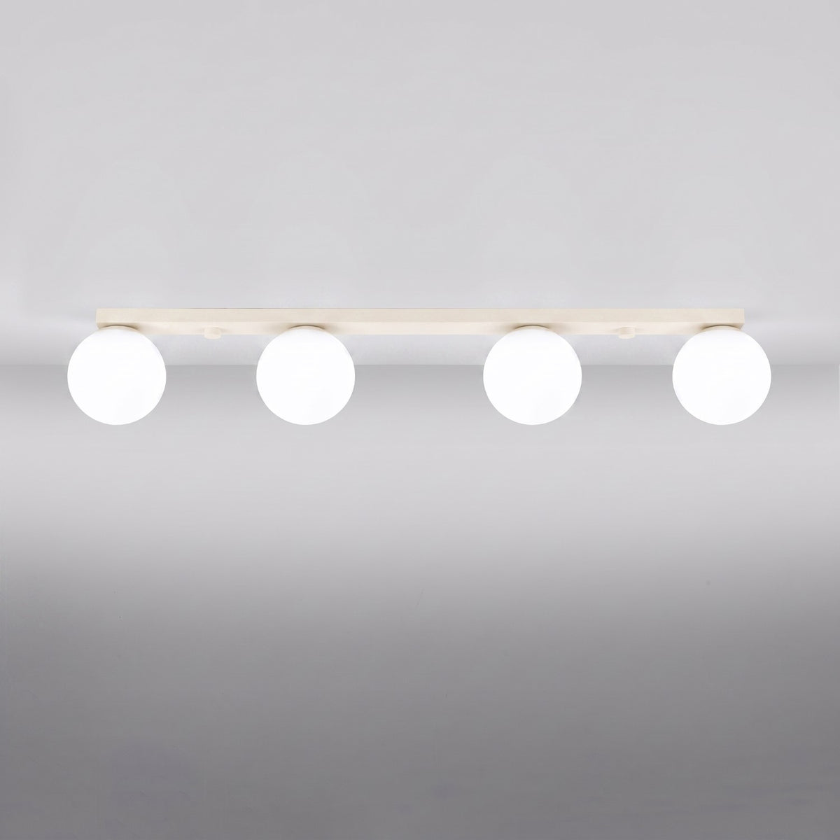 Vue rapprochée du luminaire allumé, montrant les quatre globes opalins alignés.