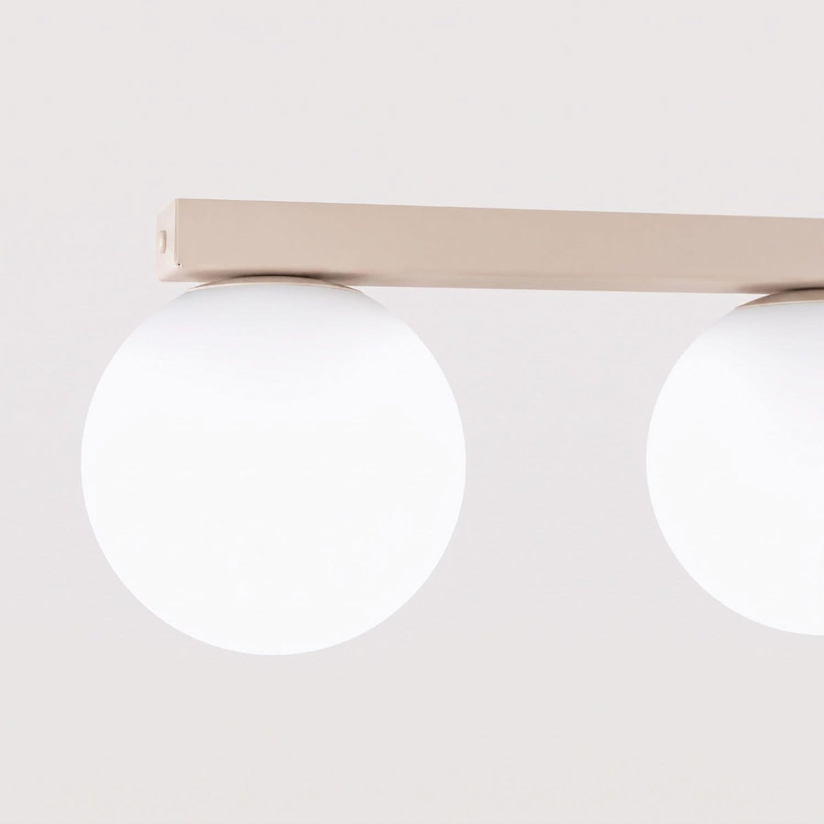 Gros plan sur la barre rectangulaire et deux globes opalins éteints.