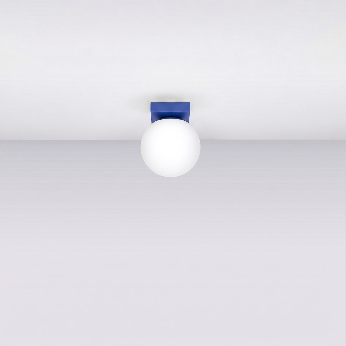 Plafonnier monté au plafond, éteint, avec socle bleu et globe blanc.