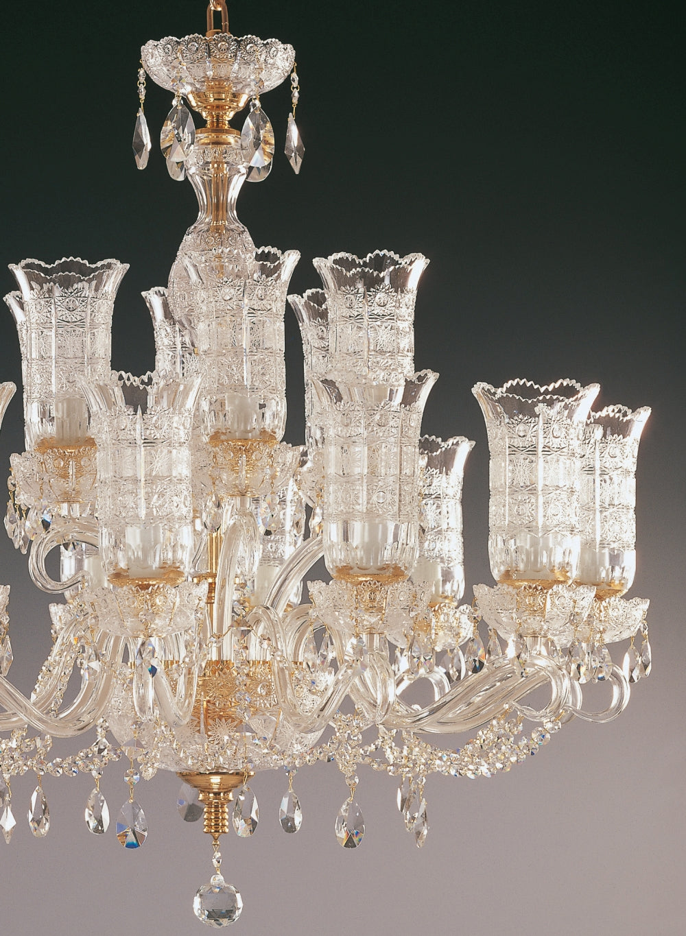 Détail des bras courbes en verre transparent et des bobèches dorées ouvragées.