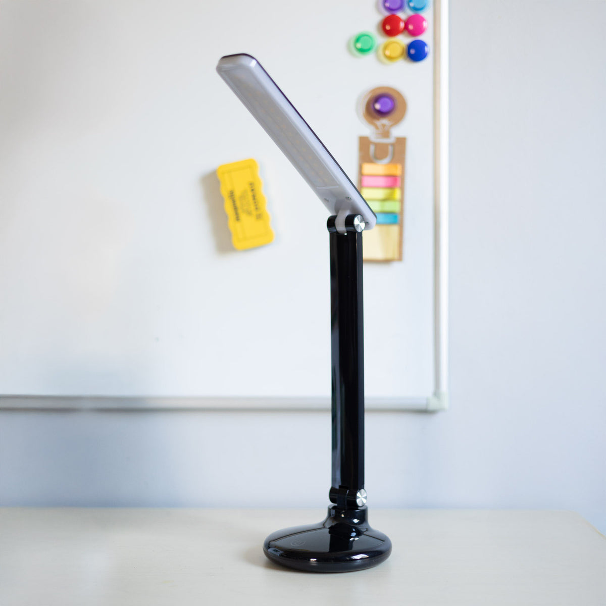 Lampe posée sur un bureau devant un tableau blanc et des notes colorées