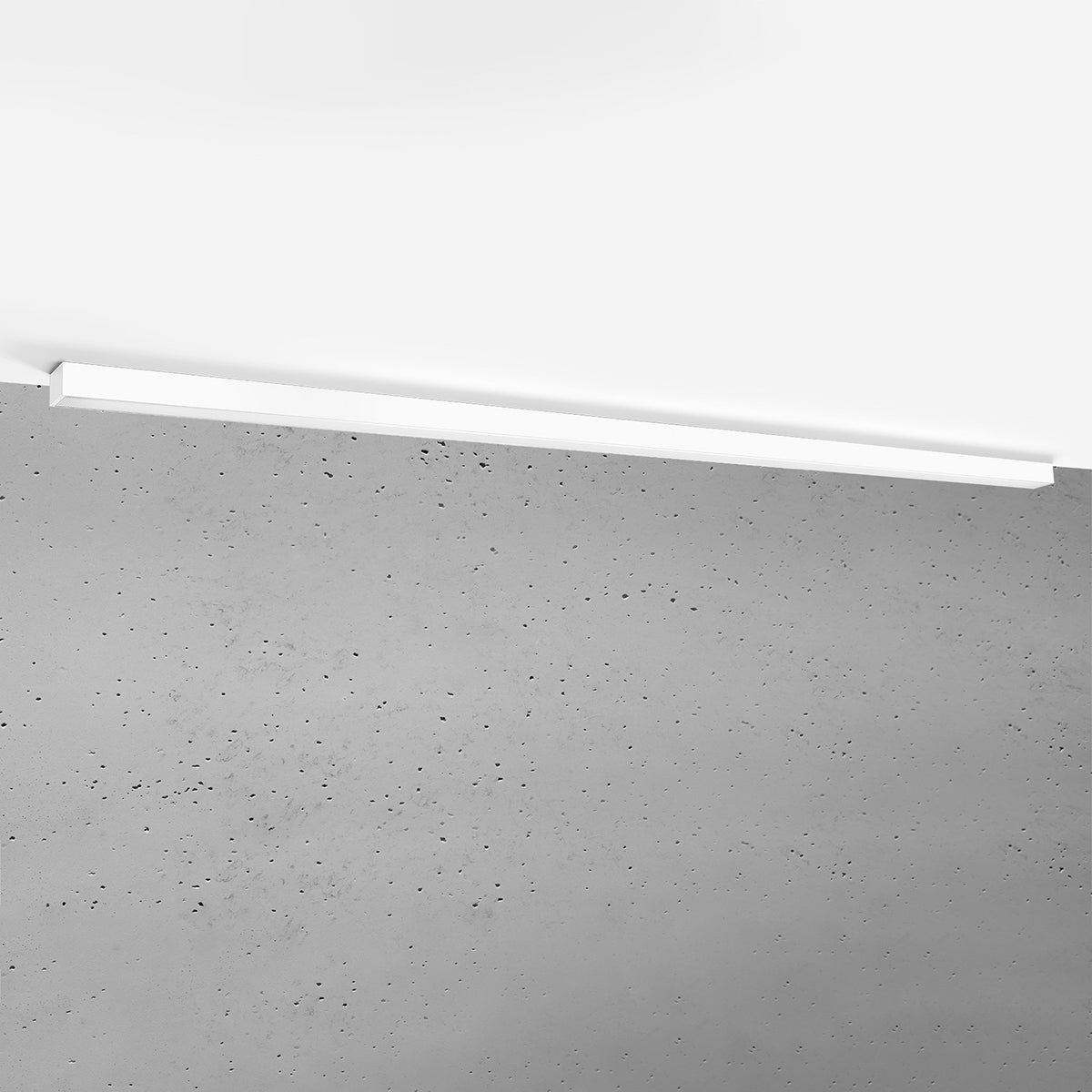 Luminaire éteint fixé au plafond devant un mur en béton brut taché