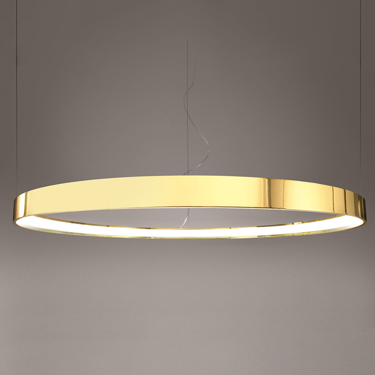 Détail de l'anneau lumineux LED allumé, finition or poli et diffuseur blanc.