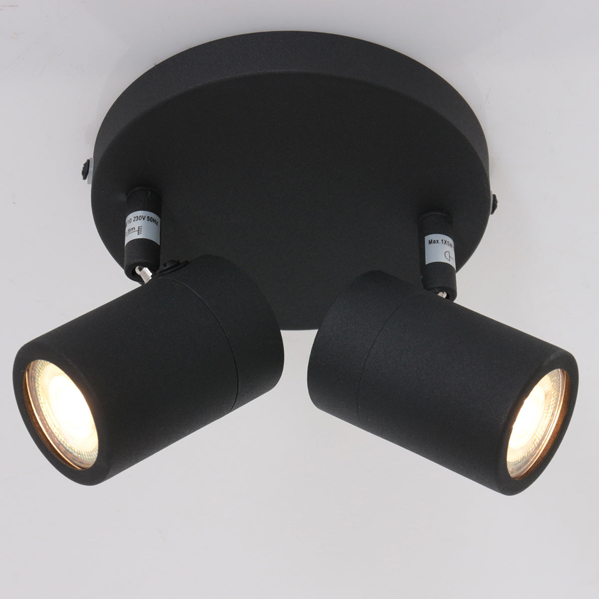 Gros plan des deux tubes cylindriques éclairés sur fond blanc uni.