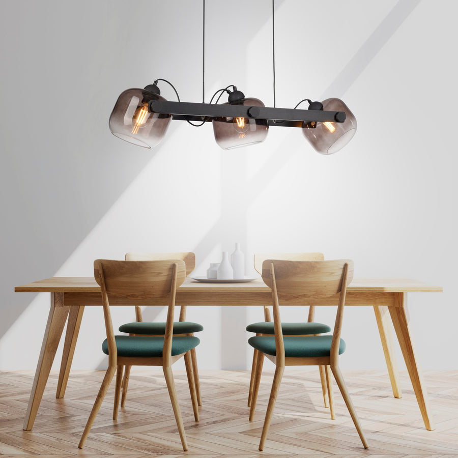 Suspension installée au-dessus d'une table à manger en bois avec chaises vertes