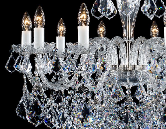 Détail des bras courbes en cristal, coupelles et pampilles taillées reflétant la lumière.