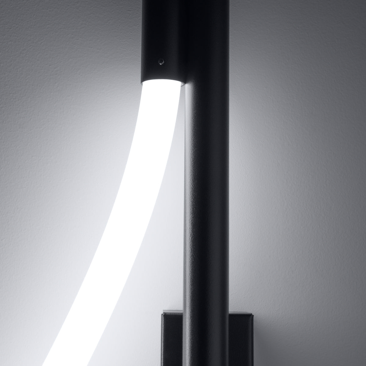 Gros plan sur la sortie du tube lumineux allumé sous le cylindre noir.
