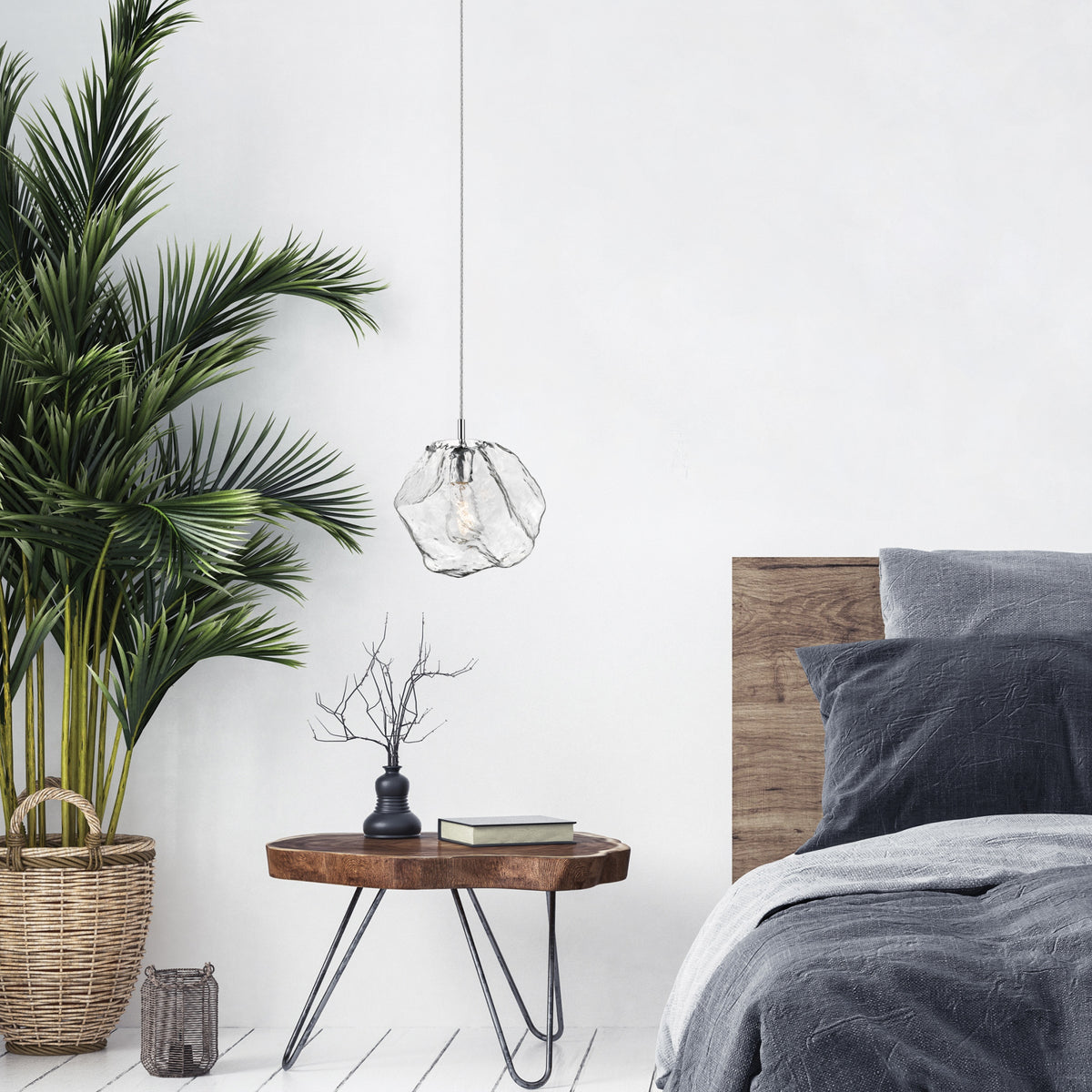 Mise en ambiance chambre avec suspension allumée au-dessus d’une table de chevet en bois.