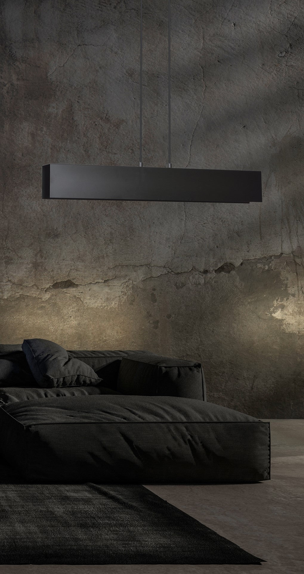 Ambiance sombre avec mur béton brut et suspension linéaire noire éclairant vers le bas