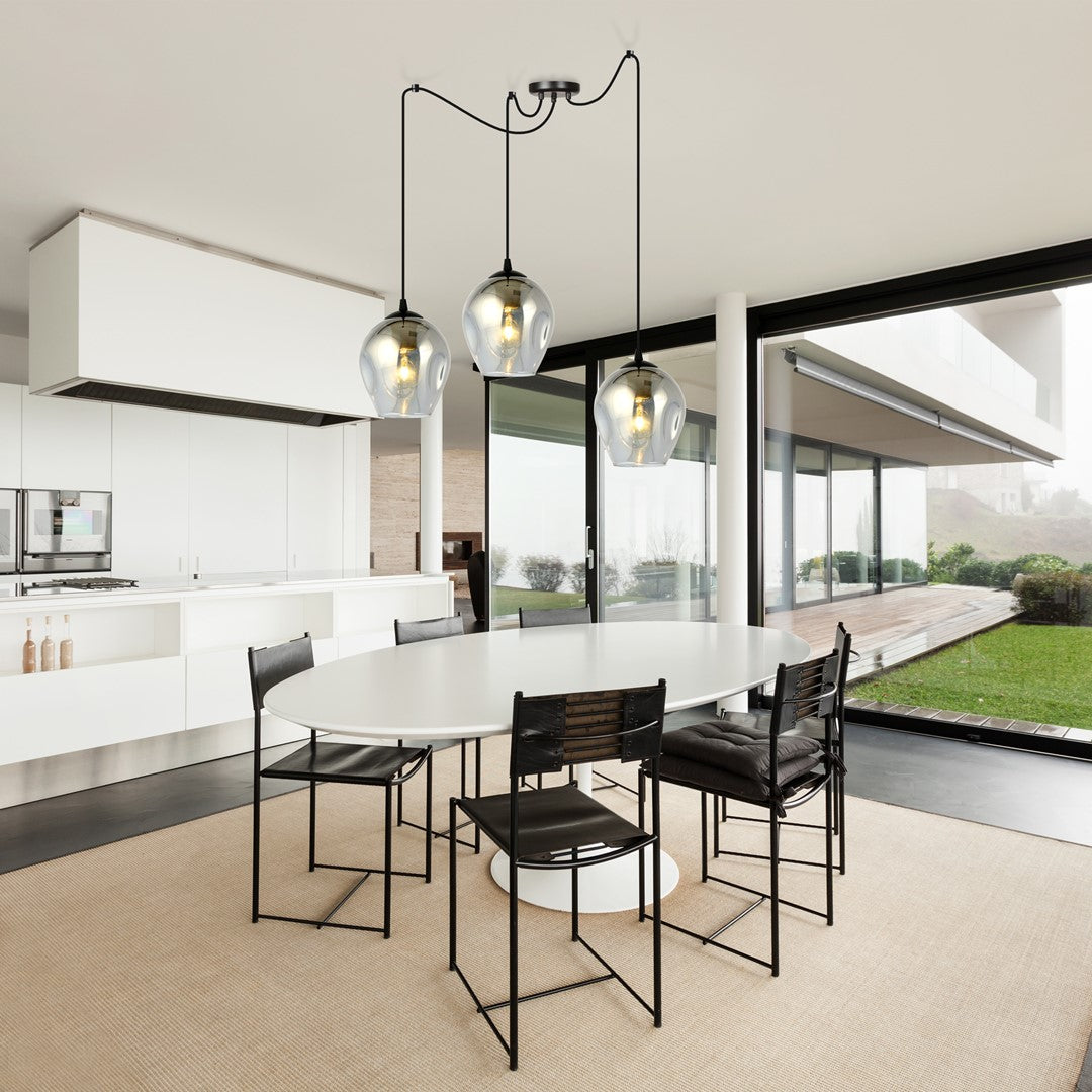 Mise en ambiance : trois suspensions au-dessus d'une table ovale dans une cuisine ouverte