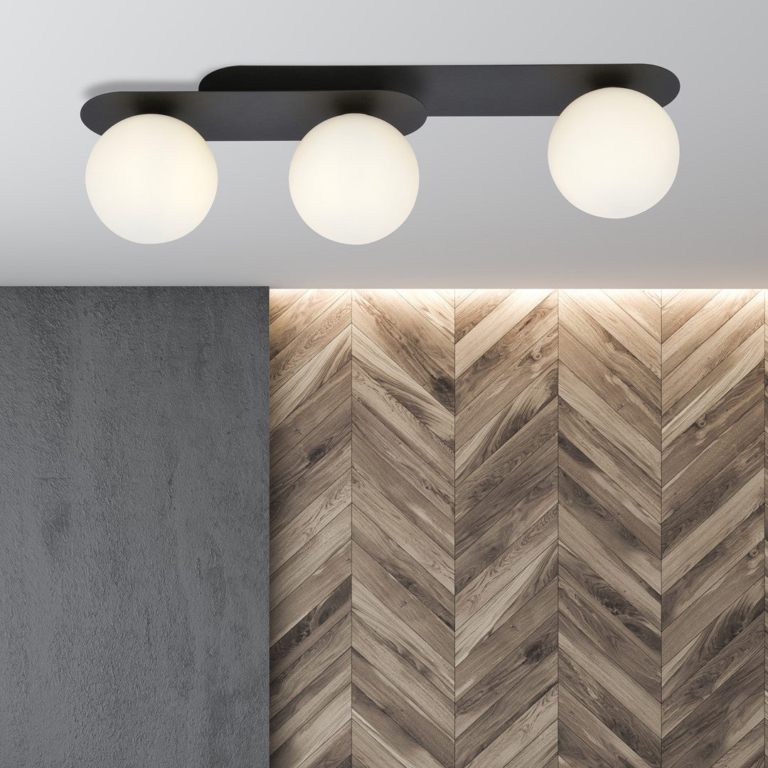Mise en ambiance du plafonnier trois lumières devant béton gris et bois chevrons