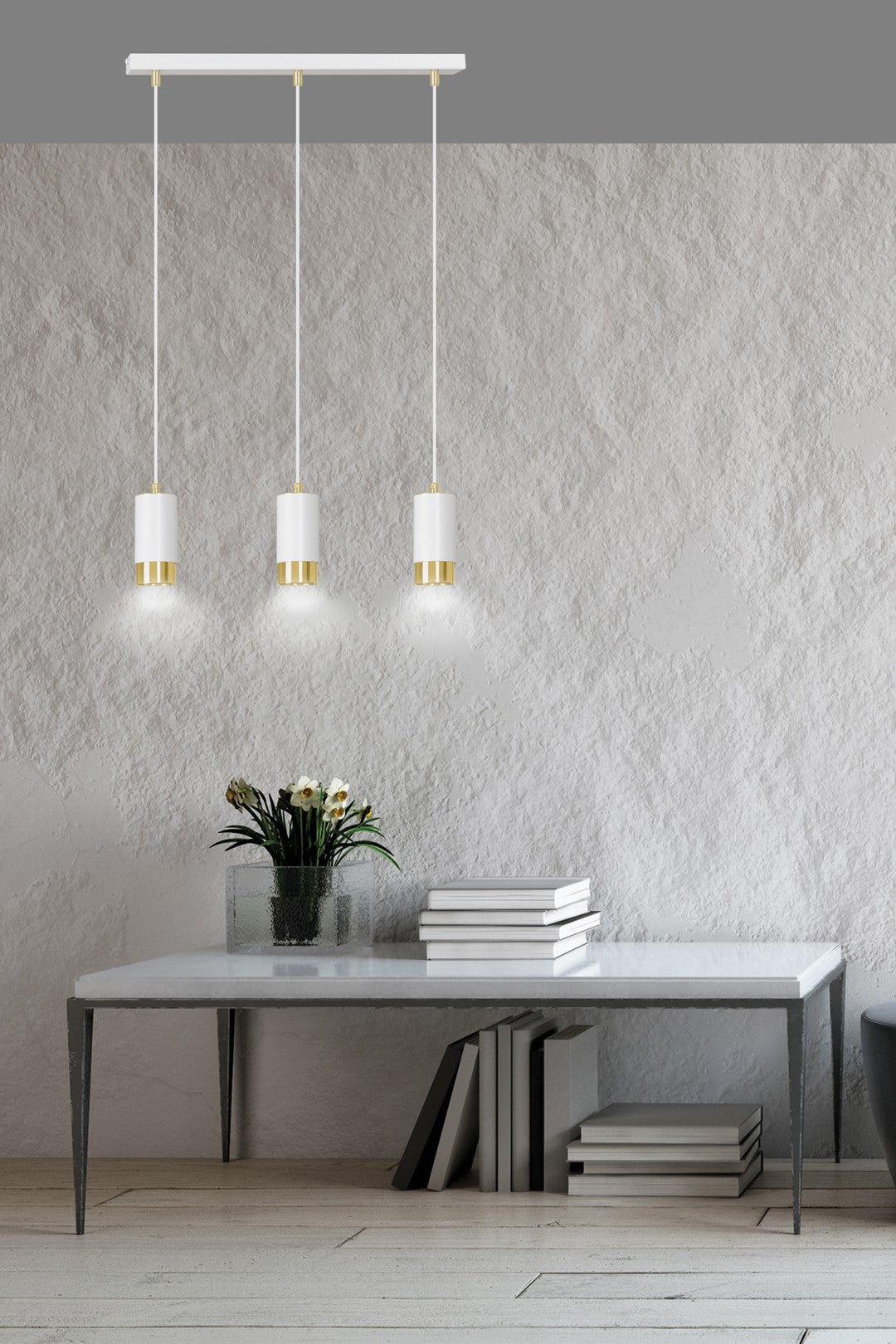 Mise en ambiance au-dessus d'une table blanche, suspension trois points allumée éclairant livres et fleurs.