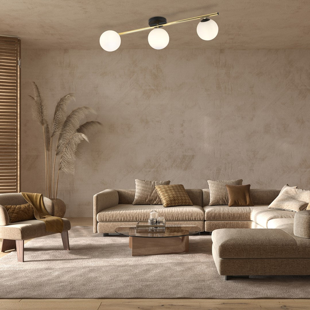 Mise en ambiance salon, plafonnier trois globes au-dessus d'un canapé beige.