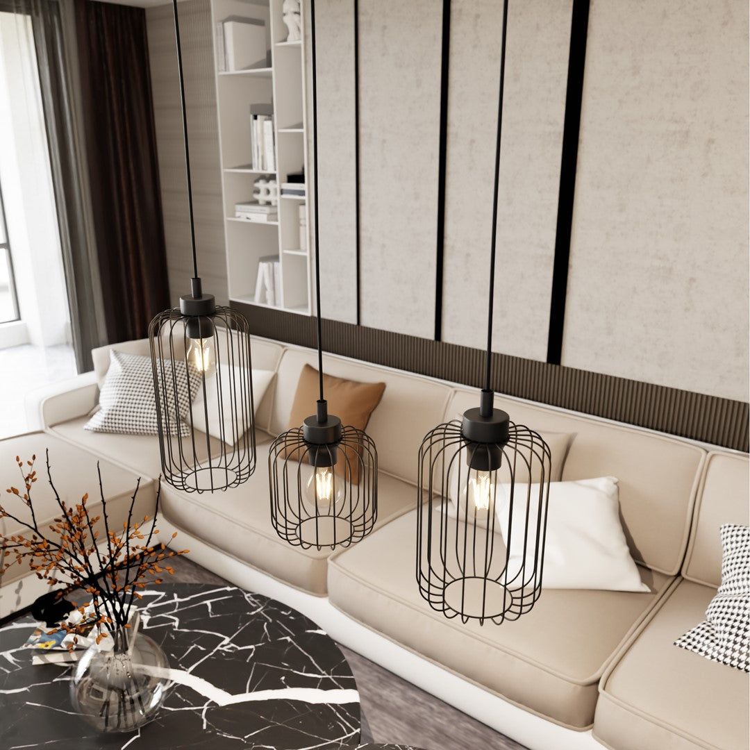 Trois cages noires suspendues au-dessus d'un canapé beige garni de coussins