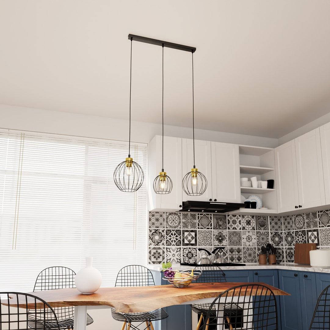Suspension trois lumières noire et dorée au-dessus d'une table dans une cuisine.