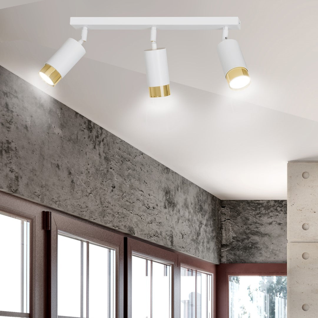 Vue rapprochée du luminaire allumé au plafond, éclairant un mur gris texturé et des fenêtres.