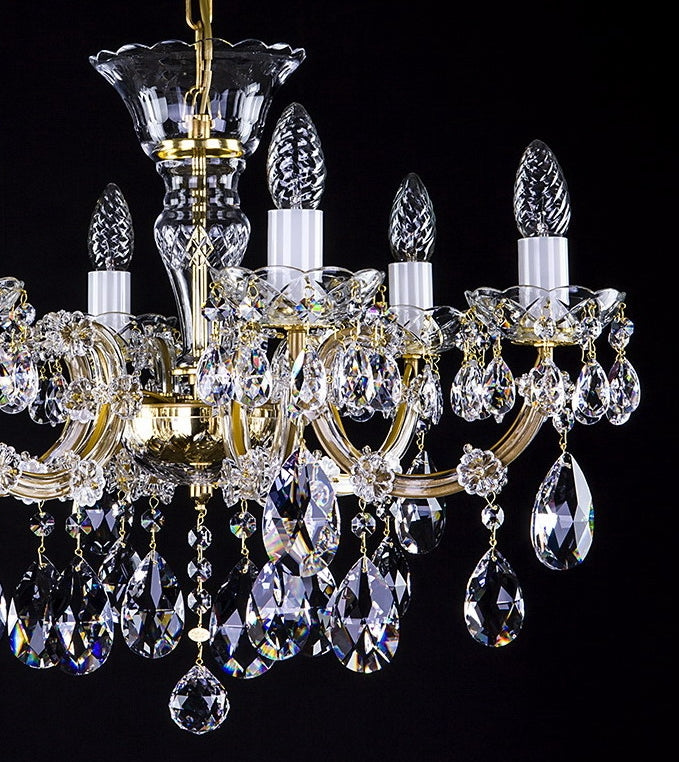 Gros plan sur la partie basse du lustre doré et ses pendeloques de cristal facetté