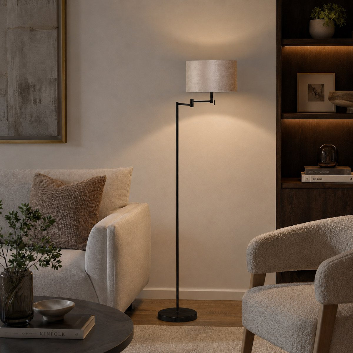 Mise en ambiance salon avec lampadaire allumé près d'un canapé et d'une bibliothèque.