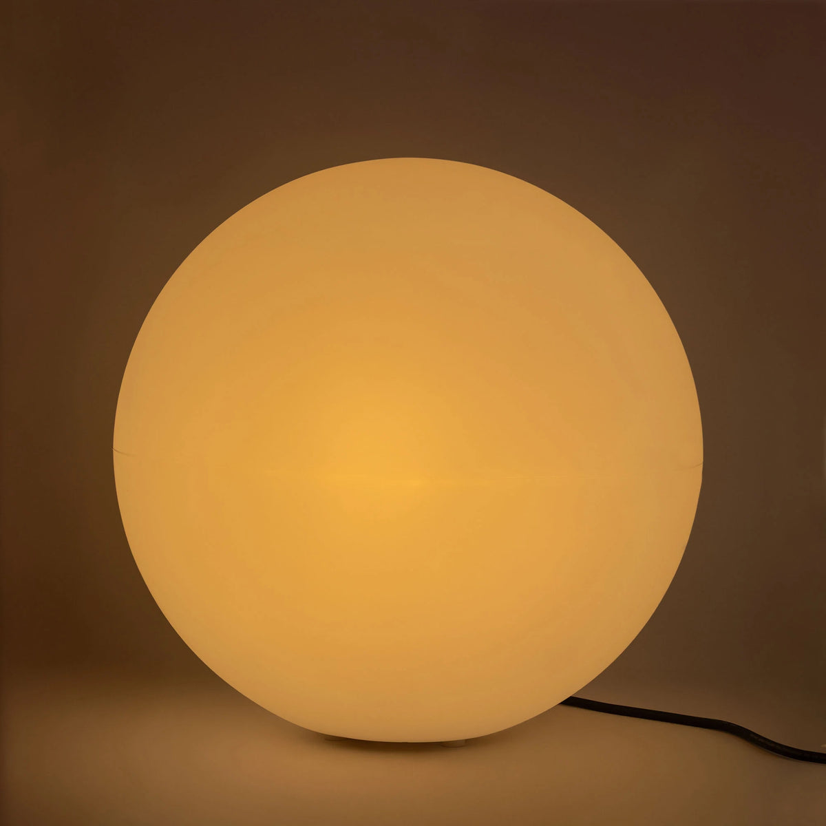Boule allumée diffusant une lumière chaude et uniforme sur fond sombre