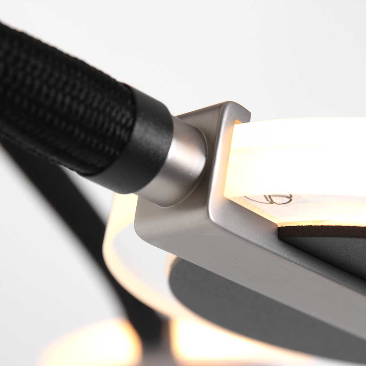Détail du raccord entre câble tressé noir et support métallique du disque lumineux.