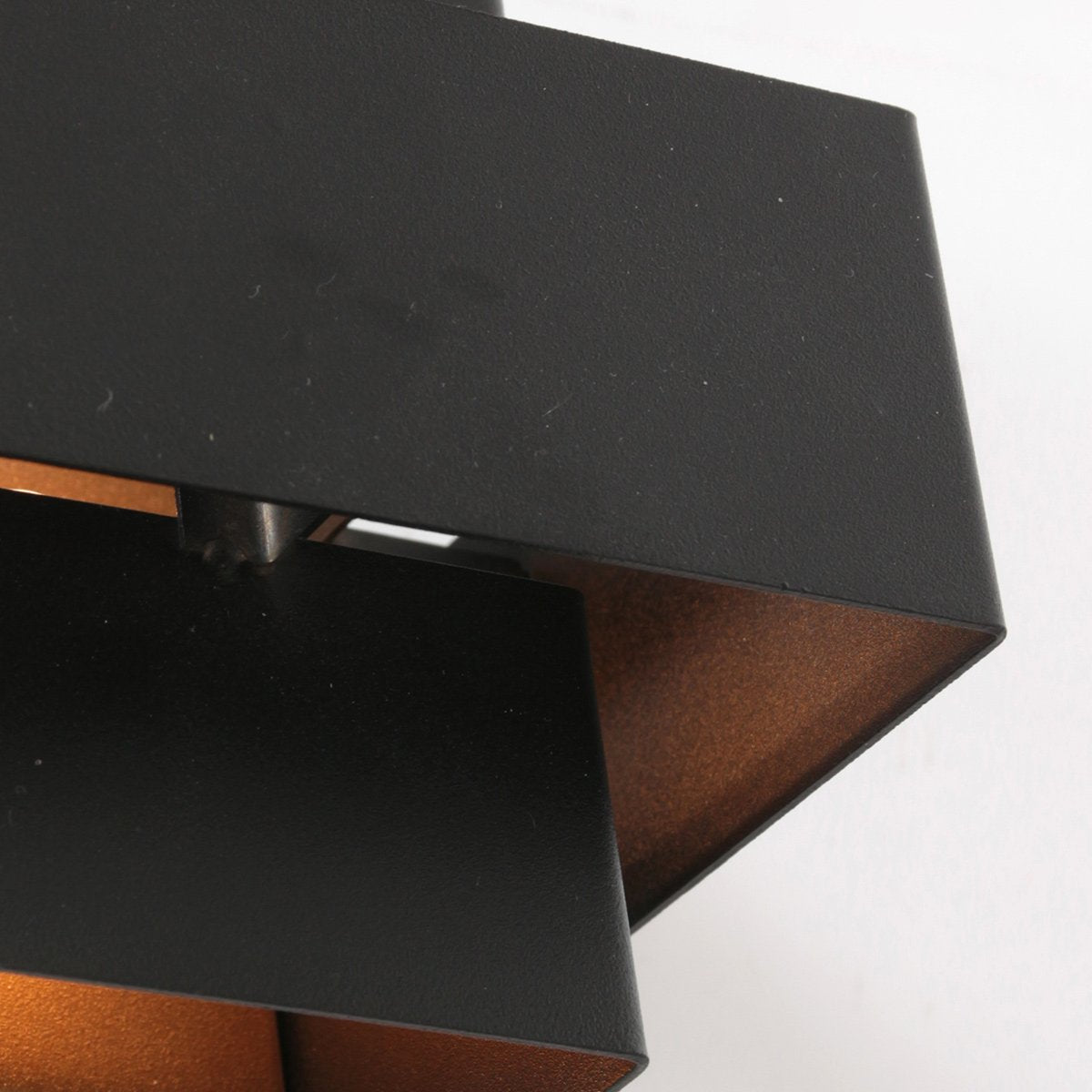 Gros plan sur la finition noire granuleuse et l'intérieur doré de l'applique.