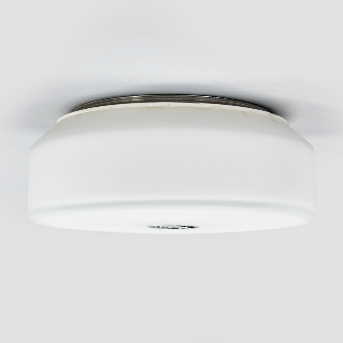 Profil latéral du plafonnier blanc fixé au plafond, montrant sa forme cylindrique et son cerclage.