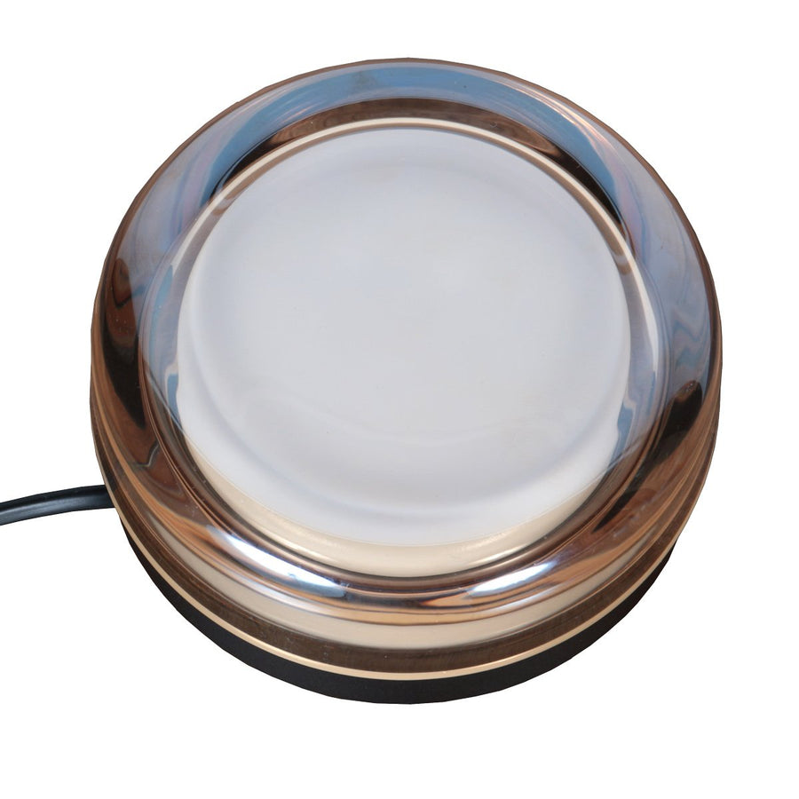 Gros plan sur le diffuseur ambré et la base noire, reflets de lumière chaude.