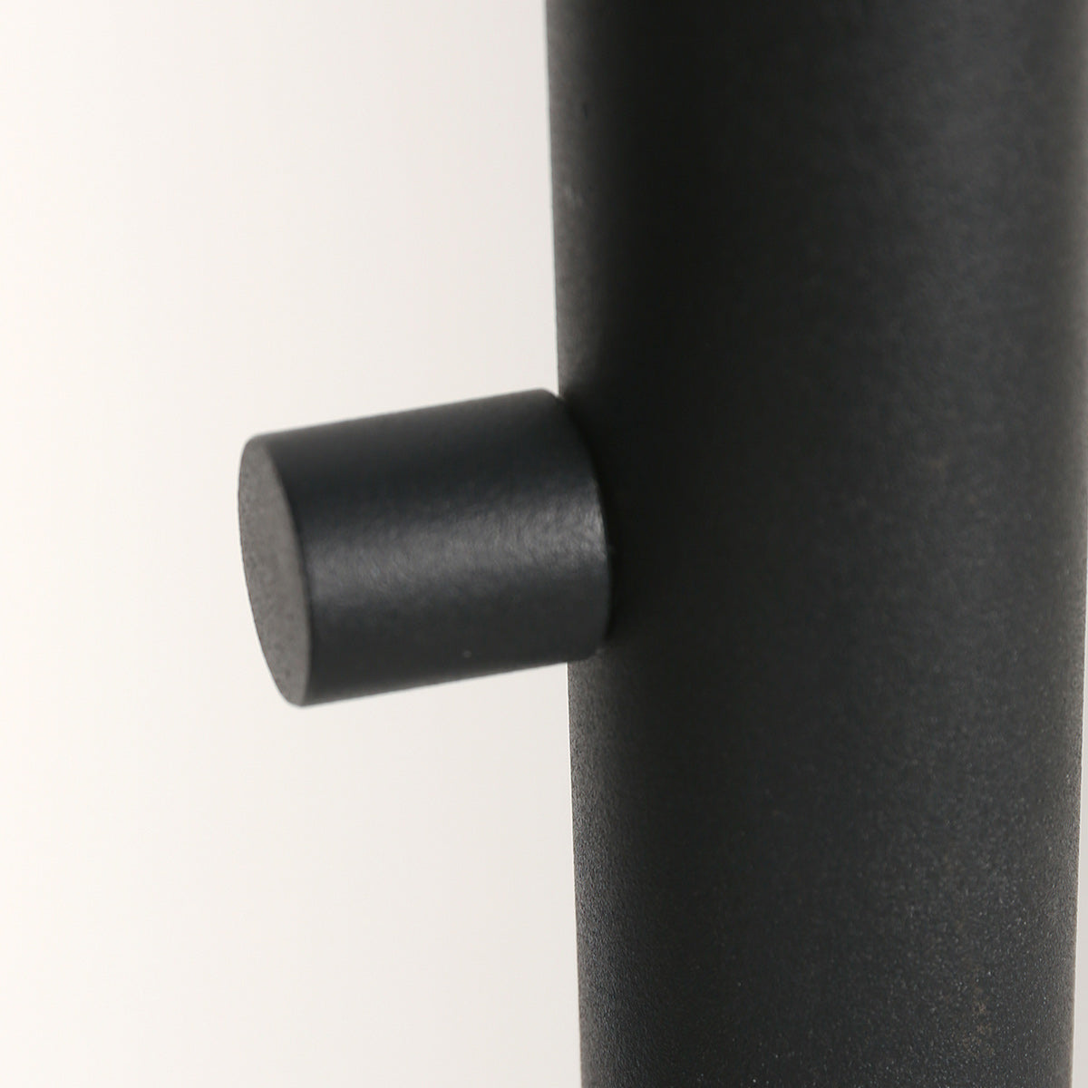 Détail d'un petit bouton cylindrique noir en saillie sur le fût métallique