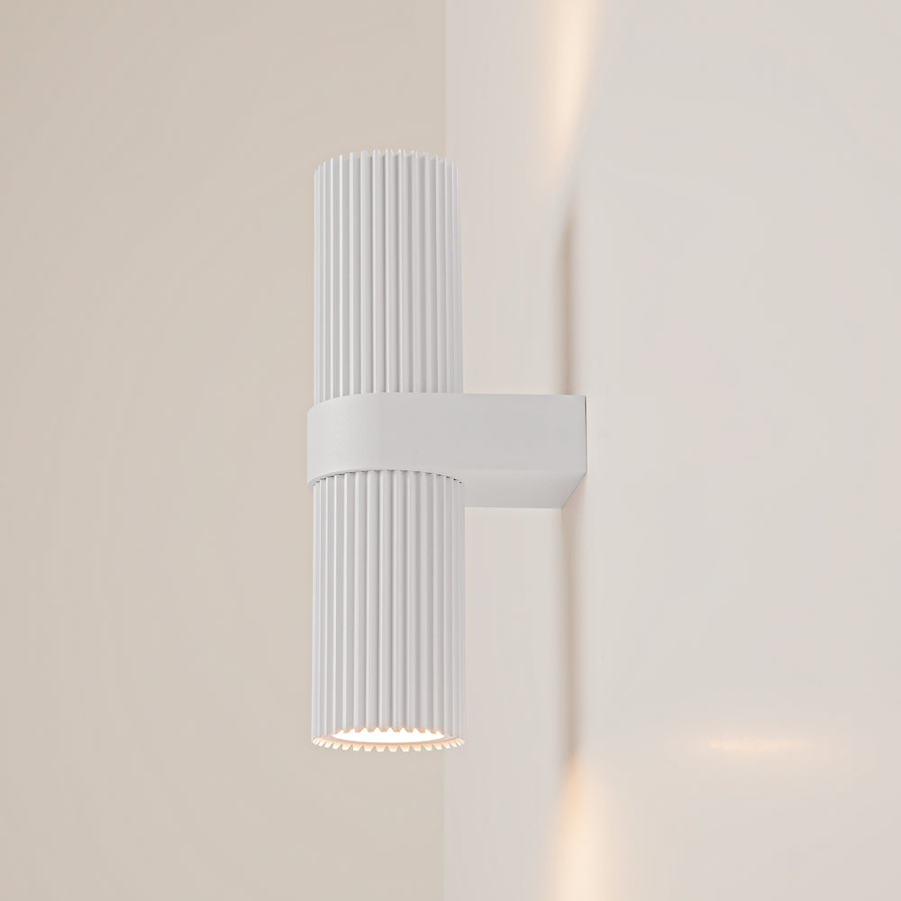 Vue de trois quarts de l'applique blanche fixée au mur, lumière allumée