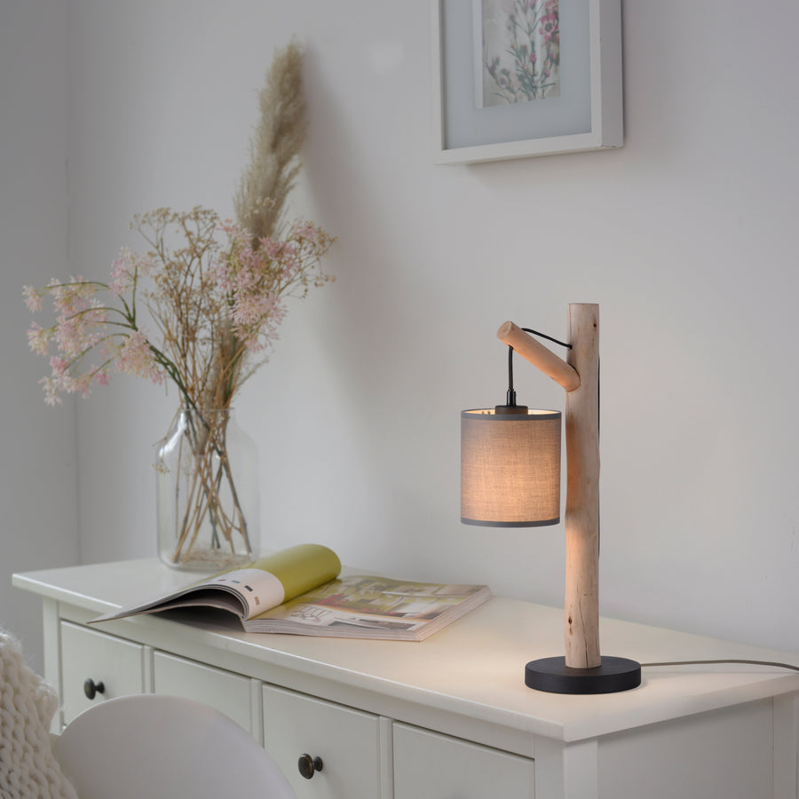 Lampe allumée posée sur une commode blanche près d'un vase de fleurs séchées