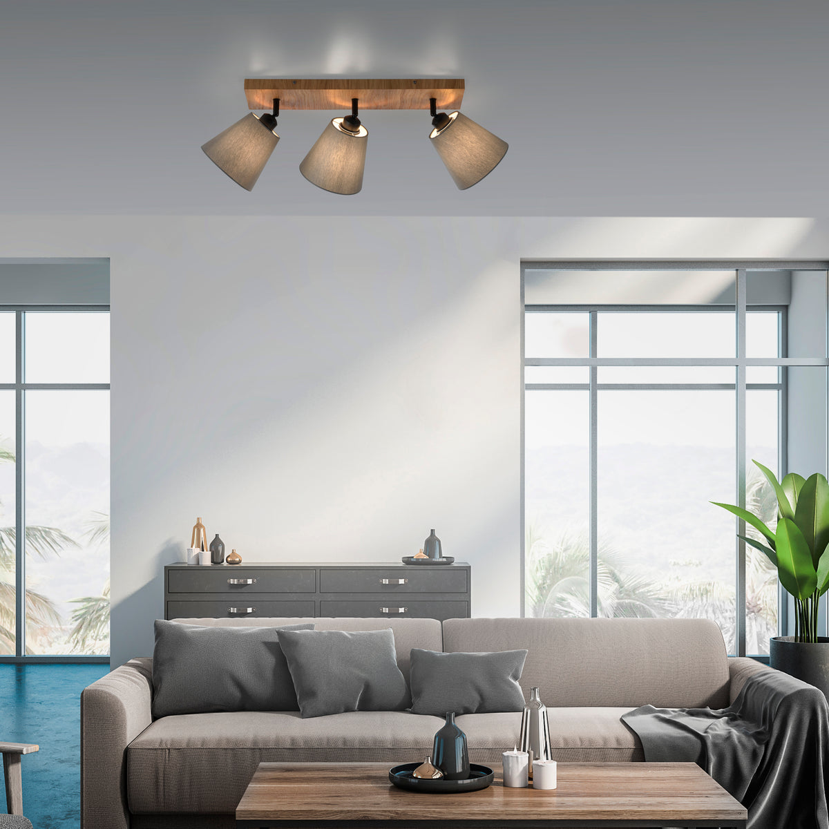 Mise en ambiance dans un salon moderne, plafonnier installé au-dessus d'un canapé gris.
