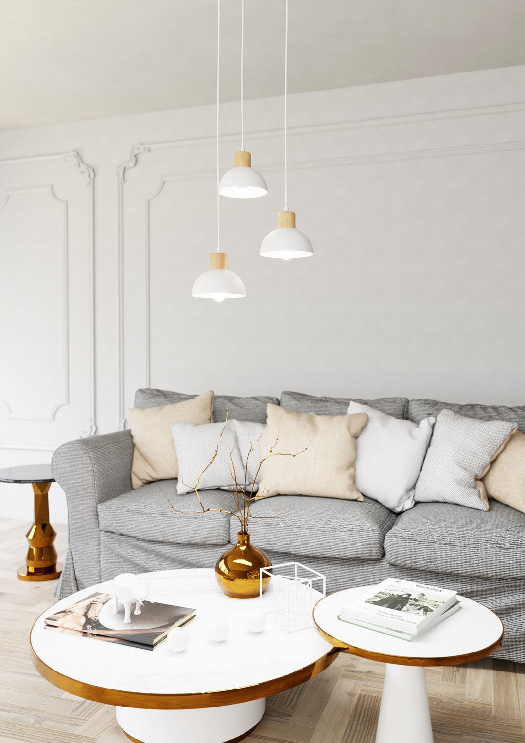 Trois suspensions éclairant un salon aux murs blancs avec canapé gris et tables basses.