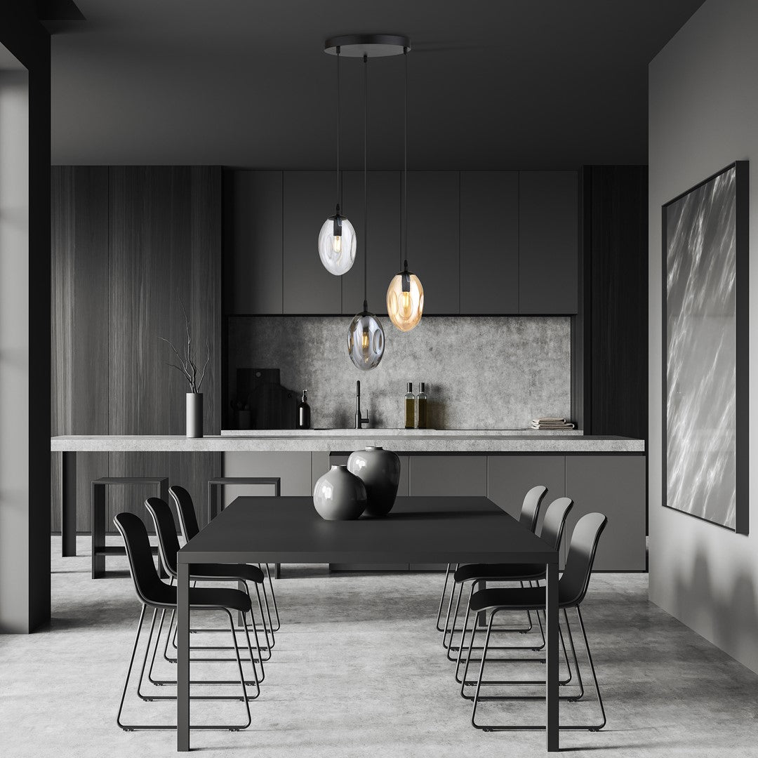 Mise en ambiance dans une cuisine sombre avec suspension noire à trois abat-jours ovales.